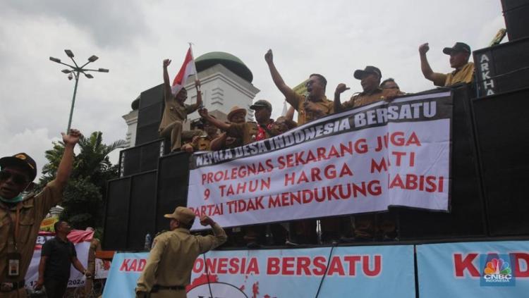 Kades demo di depan gedung DPR sambil memegang spanduk bertuliskan tuntutan jabatan 9 tahun