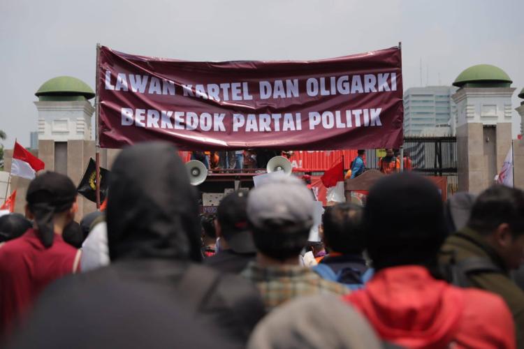 peserta aksi 22 Agustus 2024 membentangkan banner di depan gedung DPR dengan tulisan "Lawan Kartel dan Oligarki Berkedok Partai Politik"