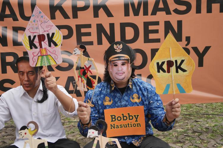 Ilustrasi: Pemeran bertopeng Bobby Nasution dan Jokowi sedang memainkan wayang berlogo KPK